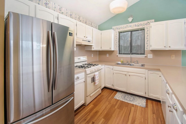 kitchen featuring light countertops, vaulted ceiling, a sink, white appliances, and under cabinet range hood