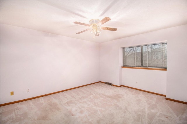 empty room with light carpet, visible vents, a ceiling fan, and baseboards