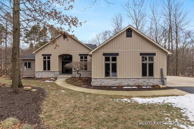 view of front of home with stone siding and roof with shingles