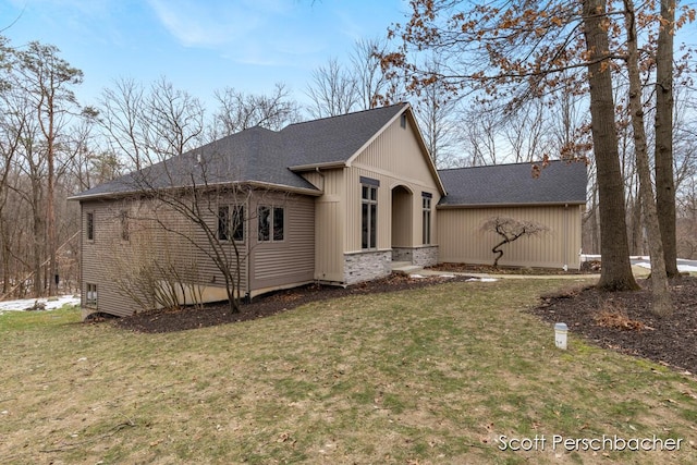 view of front of house with a shingled roof and a front lawn