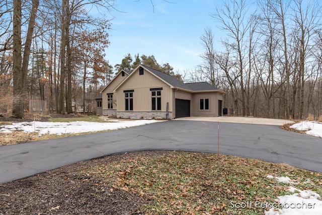 view of front facade featuring stone siding, driveway, and an attached garage