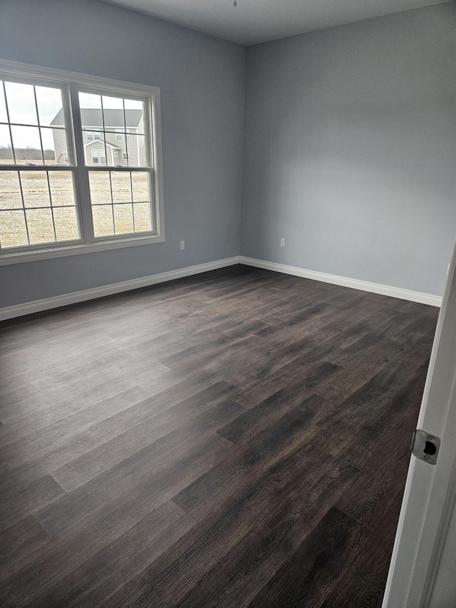 unfurnished room featuring dark wood-style flooring and baseboards