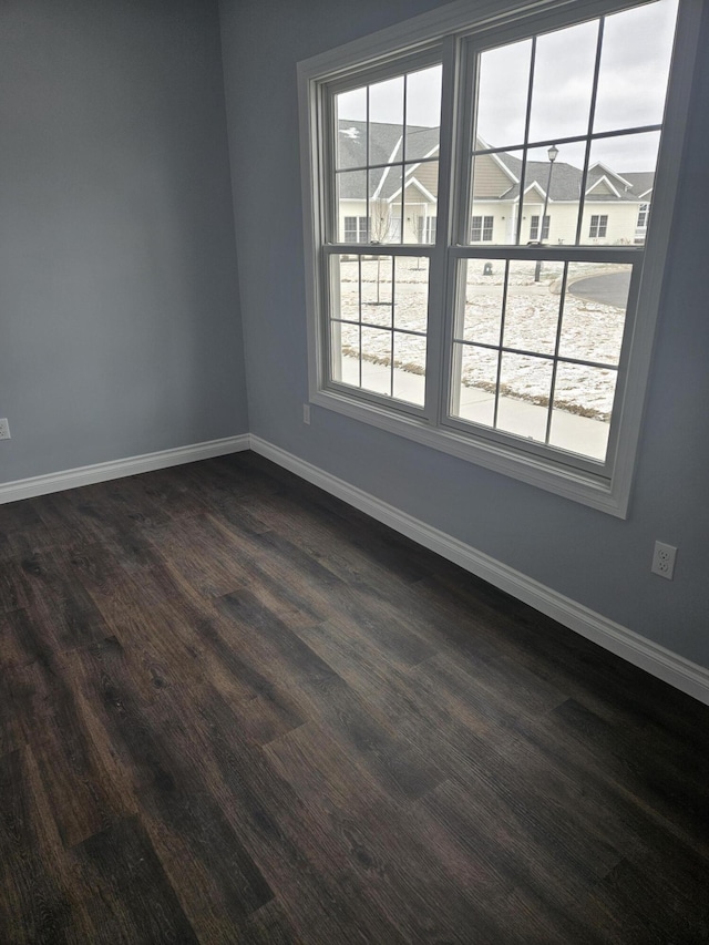 empty room featuring dark wood-style floors and baseboards