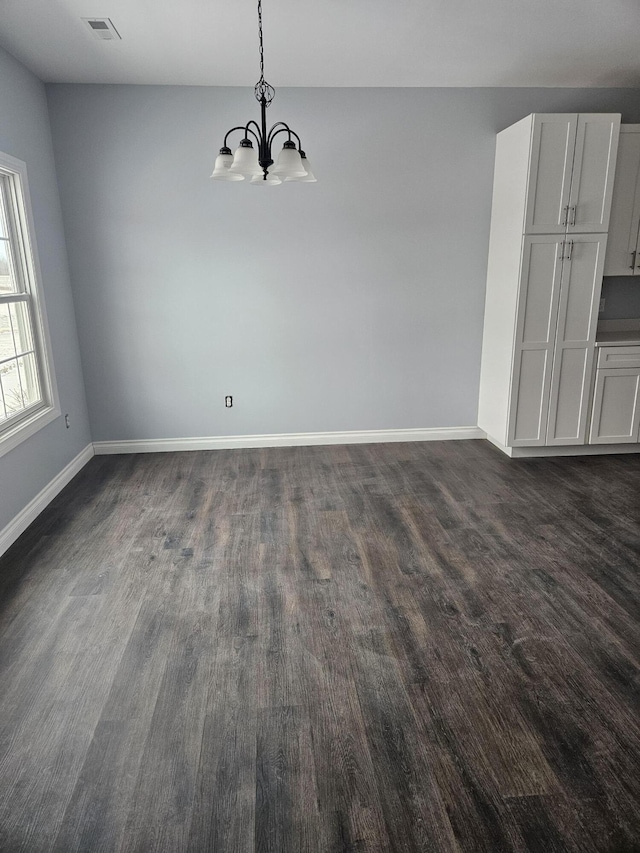 unfurnished dining area with a notable chandelier, visible vents, baseboards, and dark wood-type flooring