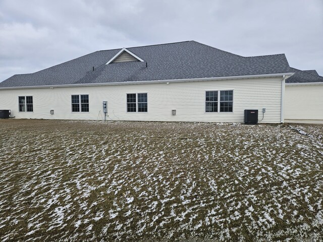 rear view of property with cooling unit and roof with shingles