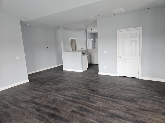 unfurnished living room featuring dark wood-style floors, visible vents, and baseboards