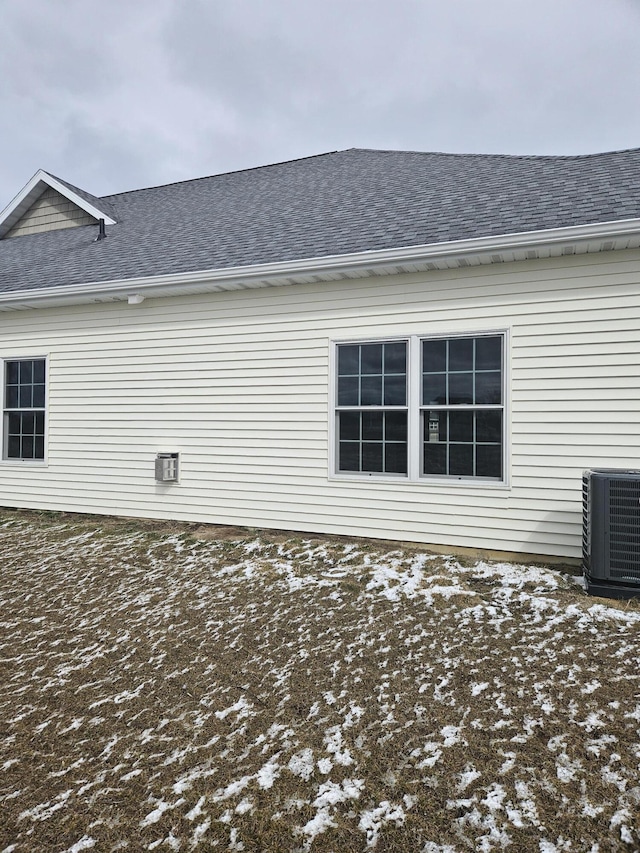 view of side of home with roof with shingles and cooling unit