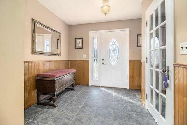 foyer entrance with a wainscoted wall and wooden walls