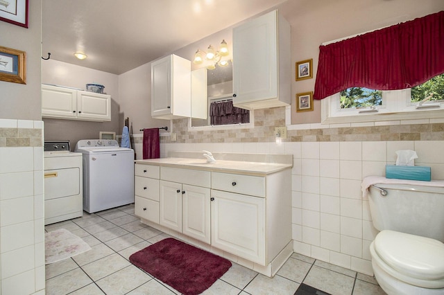 bathroom featuring washing machine and dryer, toilet, vanity, tile walls, and tile patterned floors