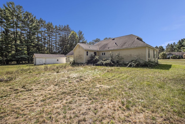 rear view of house with a lawn and an outdoor structure