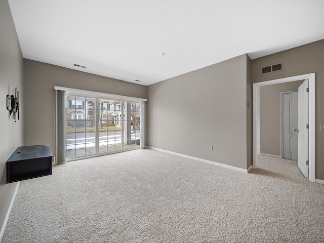 spare room with carpet floors, visible vents, and baseboards