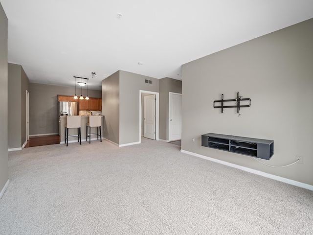 unfurnished living room with light carpet, visible vents, and baseboards