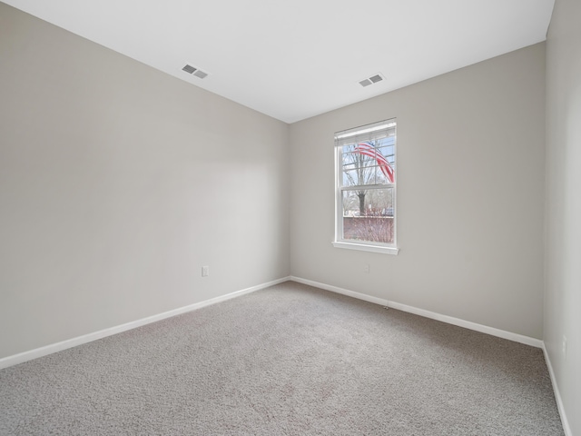 unfurnished room featuring carpet floors, visible vents, and baseboards