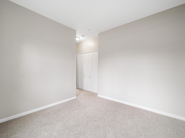 empty room featuring baseboards and light colored carpet