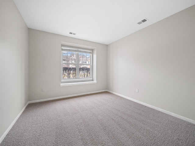 spare room with carpet flooring, visible vents, and baseboards