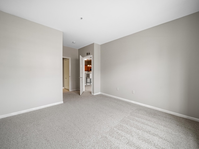 spare room featuring light carpet, visible vents, and baseboards