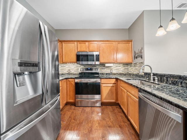 kitchen with dark wood-style floors, stainless steel appliances, tasteful backsplash, visible vents, and a sink