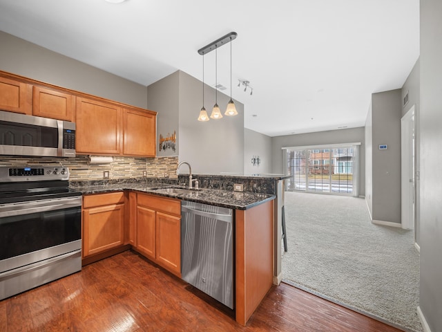 kitchen featuring stainless steel appliances, brown cabinetry, a sink, and tasteful backsplash