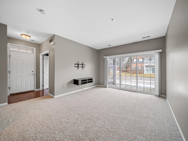 unfurnished living room with carpet, visible vents, and baseboards