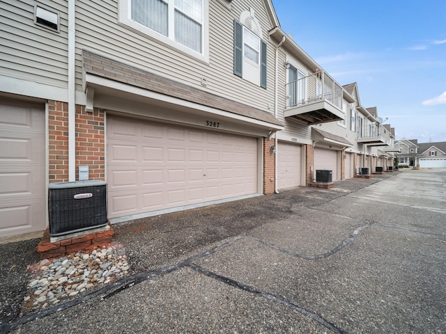 view of side of property featuring a garage, a residential view, central AC, and brick siding