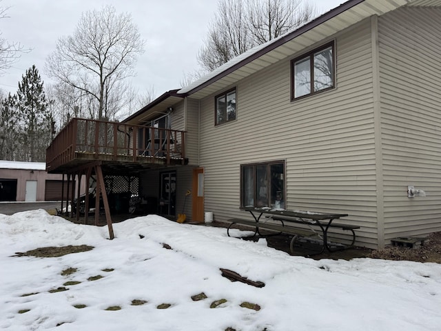 snow covered property with a garage and a wooden deck