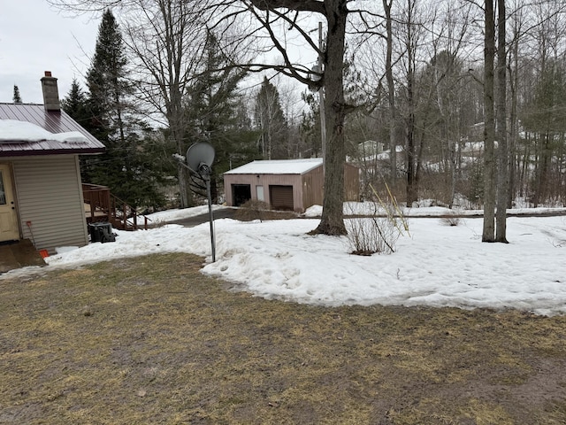 yard covered in snow with a detached garage and an outdoor structure