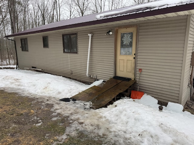 snow covered property entrance featuring metal roof