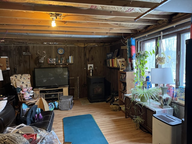 below grade area with a wood stove, wooden walls, and wood finished floors