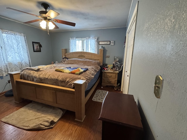 bedroom featuring ceiling fan, wood finished floors, and crown molding