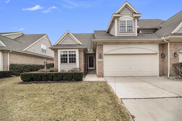 view of front of property with roof with shingles, concrete driveway, and brick siding