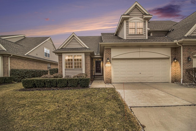 traditional home featuring concrete driveway, brick siding, roof with shingles, and a lawn