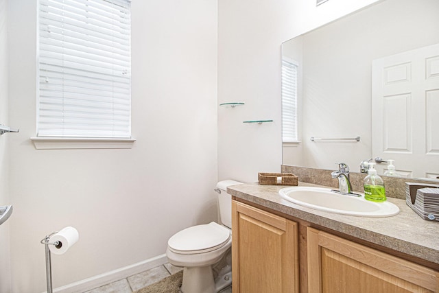 half bathroom featuring toilet, vanity, baseboards, and tile patterned floors