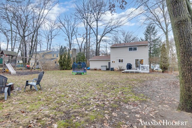 view of yard featuring a trampoline, a playground, and a wooden deck