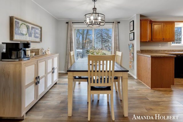 dining space with crown molding, a notable chandelier, light wood-style flooring, and baseboards