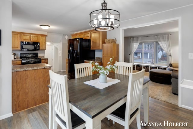 dining room featuring a notable chandelier, baseboards, and wood finished floors