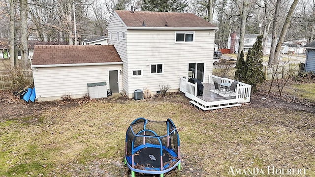 back of property featuring a shingled roof, a trampoline, fence, a deck, and cooling unit