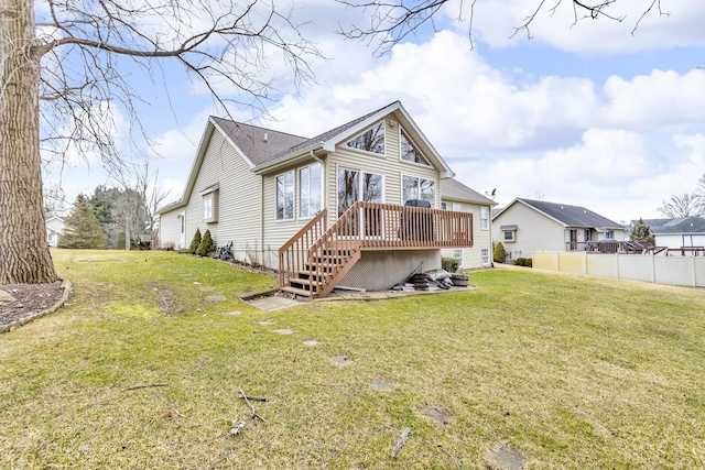 rear view of house with a lawn, a wooden deck, and fence