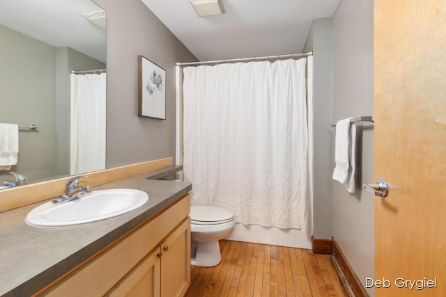bathroom with toilet, hardwood / wood-style flooring, baseboards, and vanity