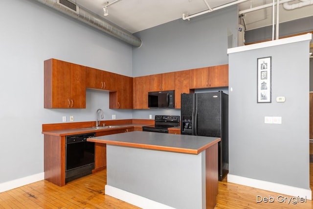 kitchen with visible vents, a high ceiling, a sink, light wood-type flooring, and black appliances