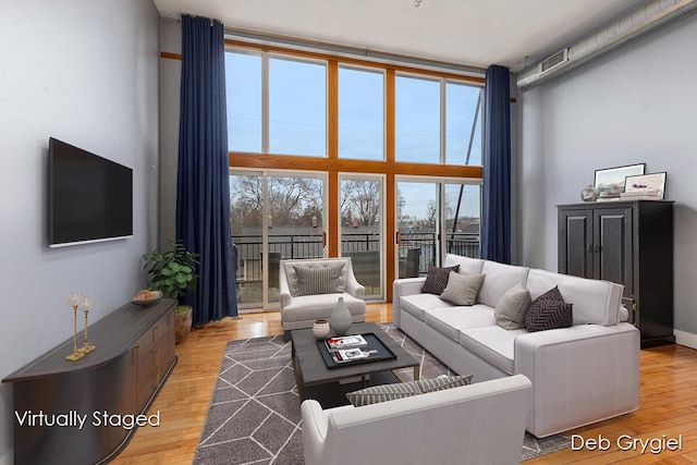 living room featuring light wood finished floors and a high ceiling