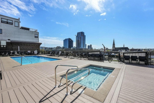 community pool featuring a view of city, a patio area, and a hot tub