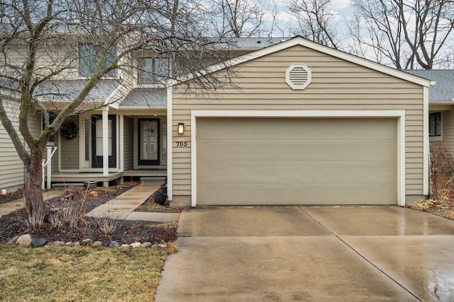 view of front facade featuring a shingled roof, concrete driveway, covered porch, and an attached garage