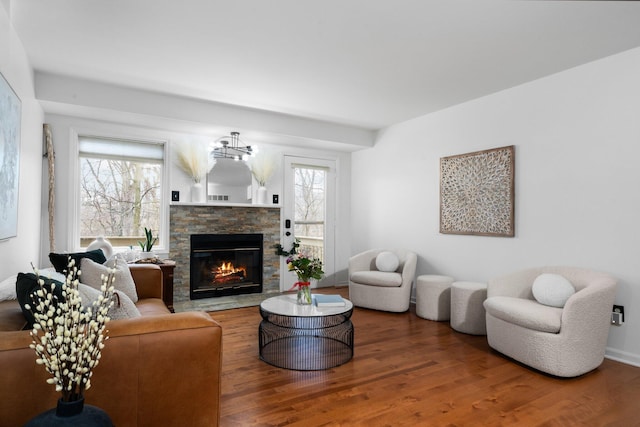 living room with a stone fireplace and wood finished floors