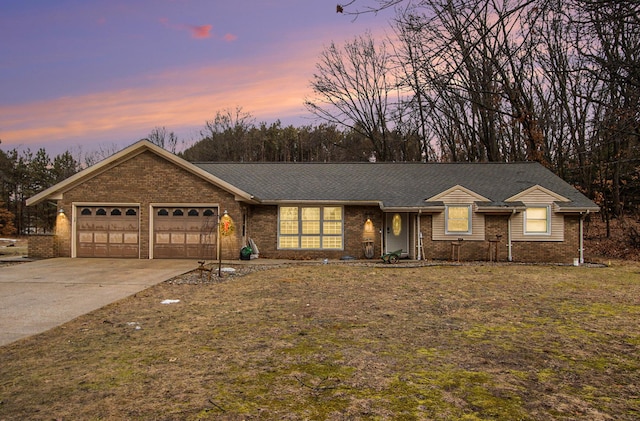 ranch-style house featuring a garage, driveway, and brick siding