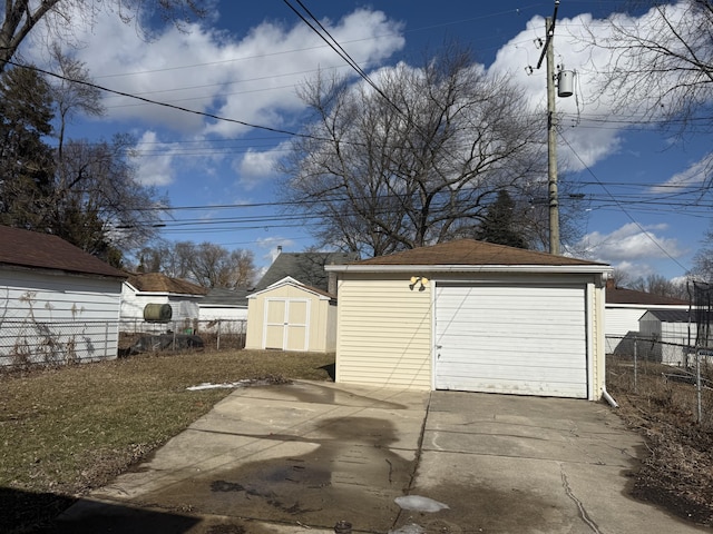 detached garage featuring driveway, a shed, and fence