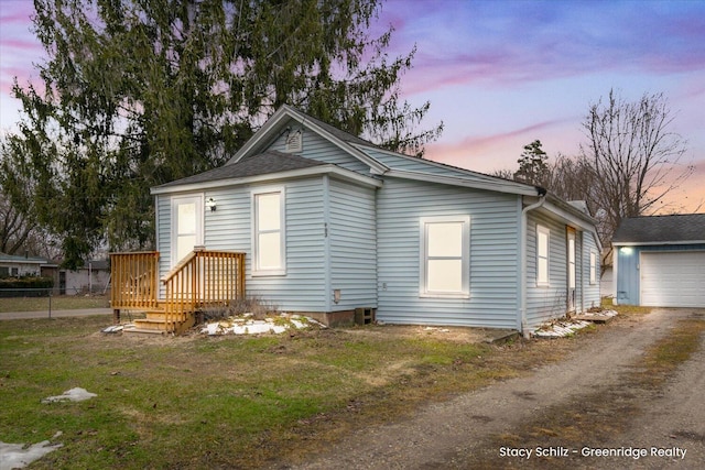 view of front of home with an outbuilding, a garage, fence, driveway, and a yard