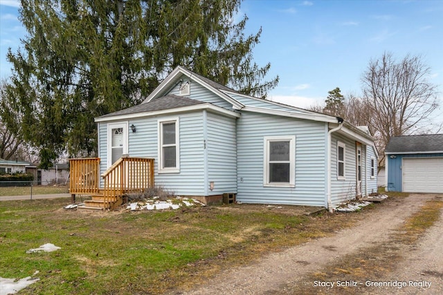 view of front of property featuring a front yard, fence, a garage, driveway, and an outdoor structure