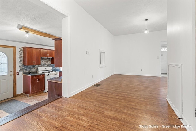 interior space featuring dark countertops, light wood-type flooring, white gas range, and visible vents