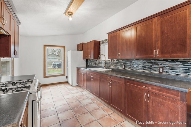 kitchen with tasteful backsplash, dark countertops, white appliances, and a sink