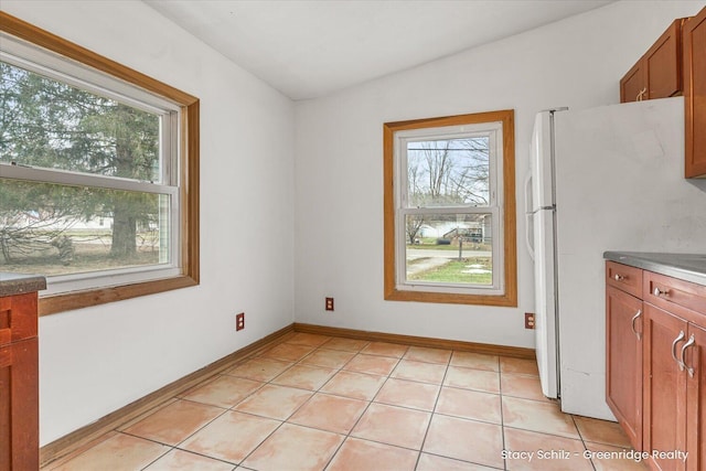 unfurnished dining area featuring a wealth of natural light, lofted ceiling, baseboards, and light tile patterned floors